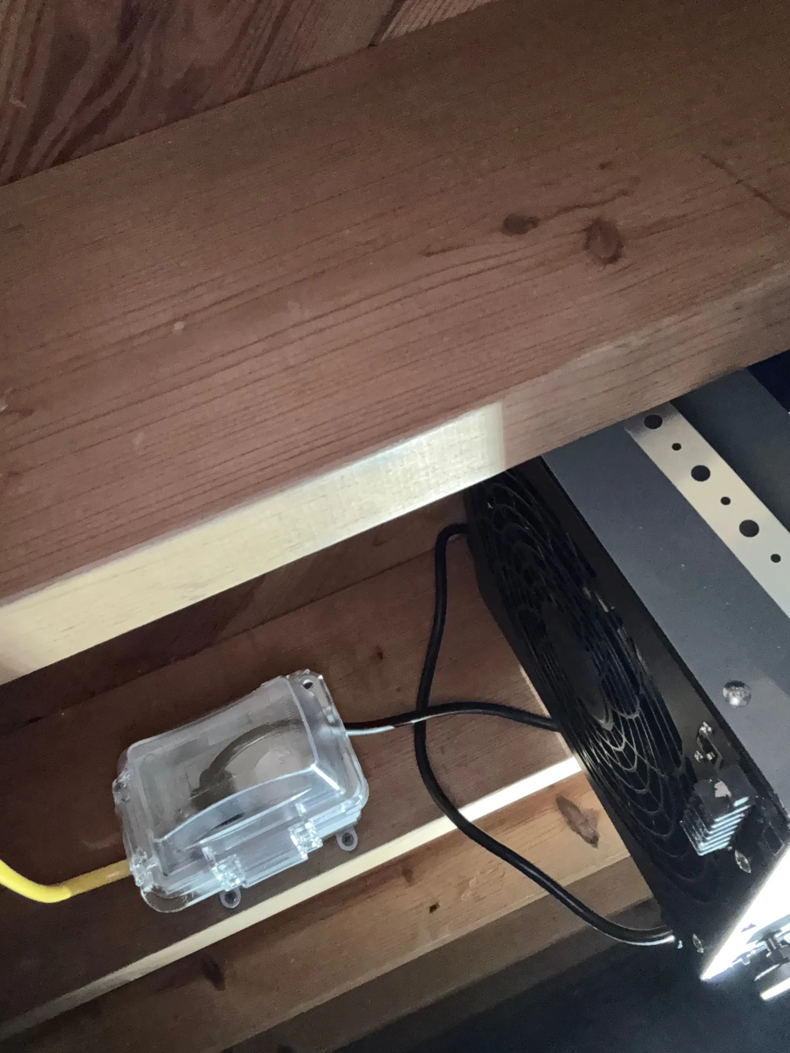 A close-up view of a new, neatly installed electrical outlet within a transparent waterproof box, attached to a wooden beam u