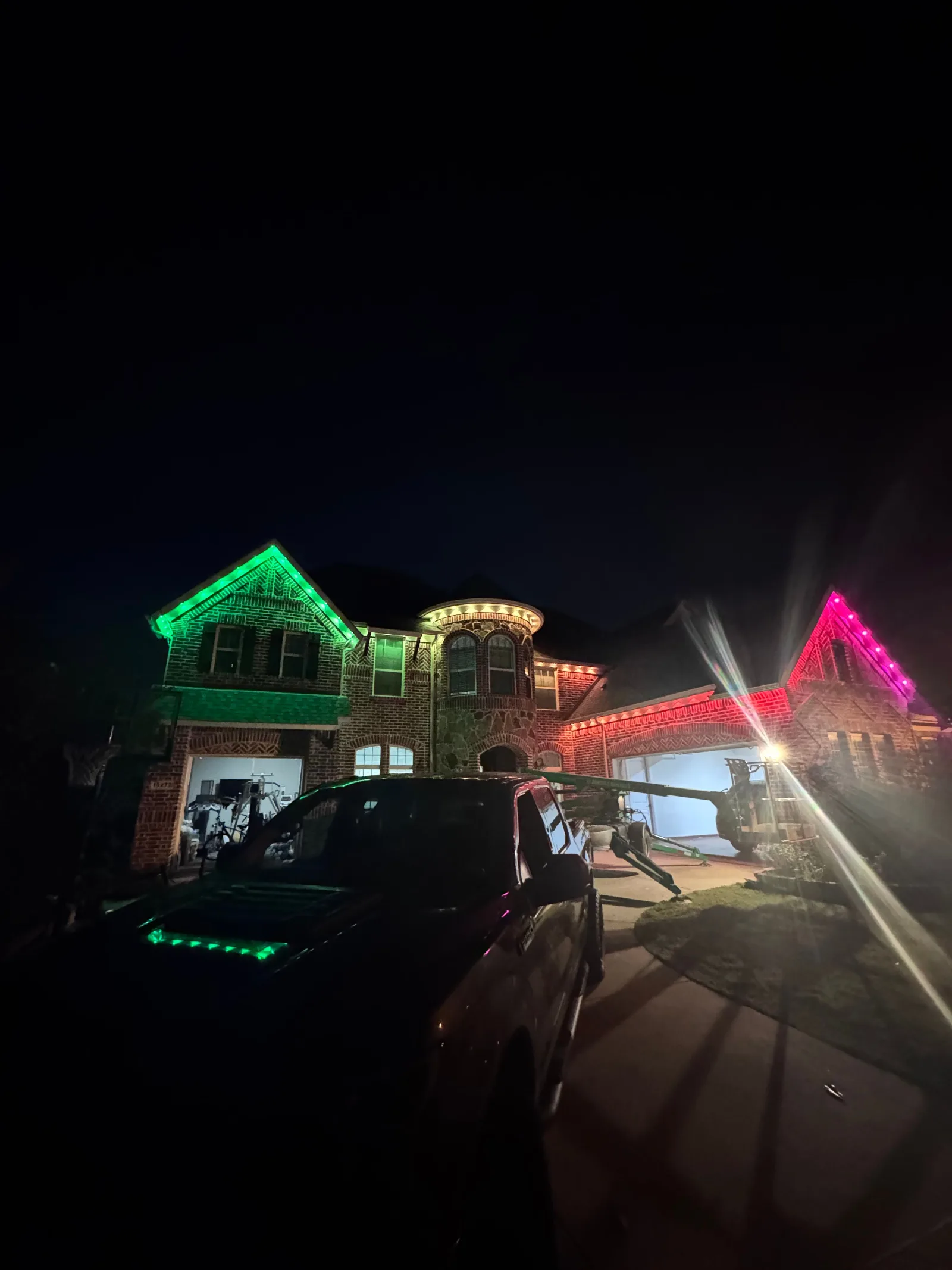 Victorian-style brick home with smart multicolored exterior lights. Rooflines are outlined in green, golden, and pink lights.