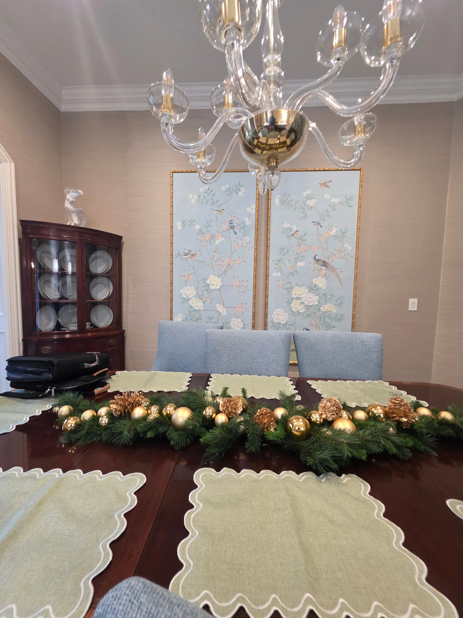 Dining room with a mahogany table, blue chairs, a corner china cabinet, and two ornate floral wall art panels.